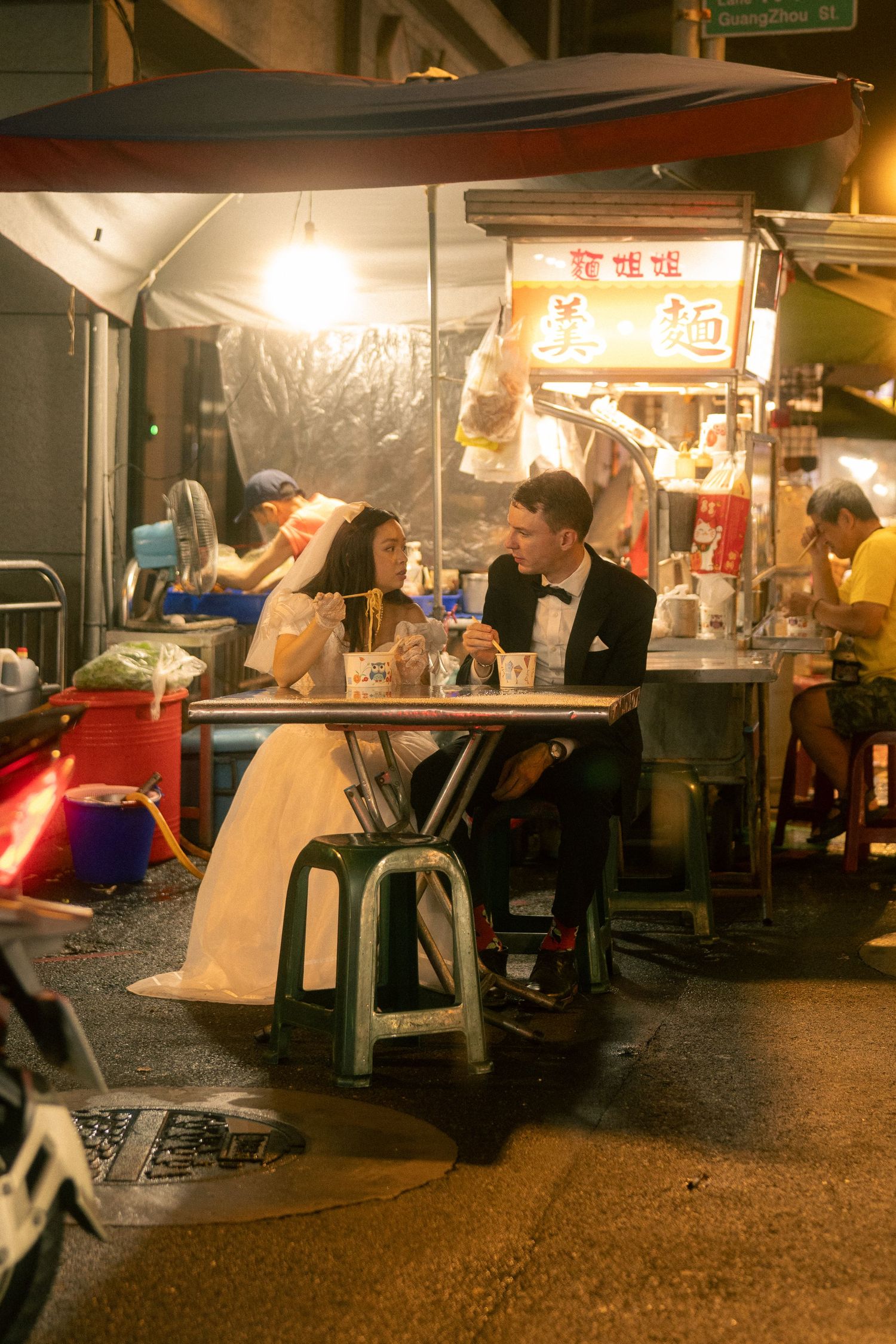Bride and groom eating noodles at a local street food stall during their Taipei pre-wedding photoshoot