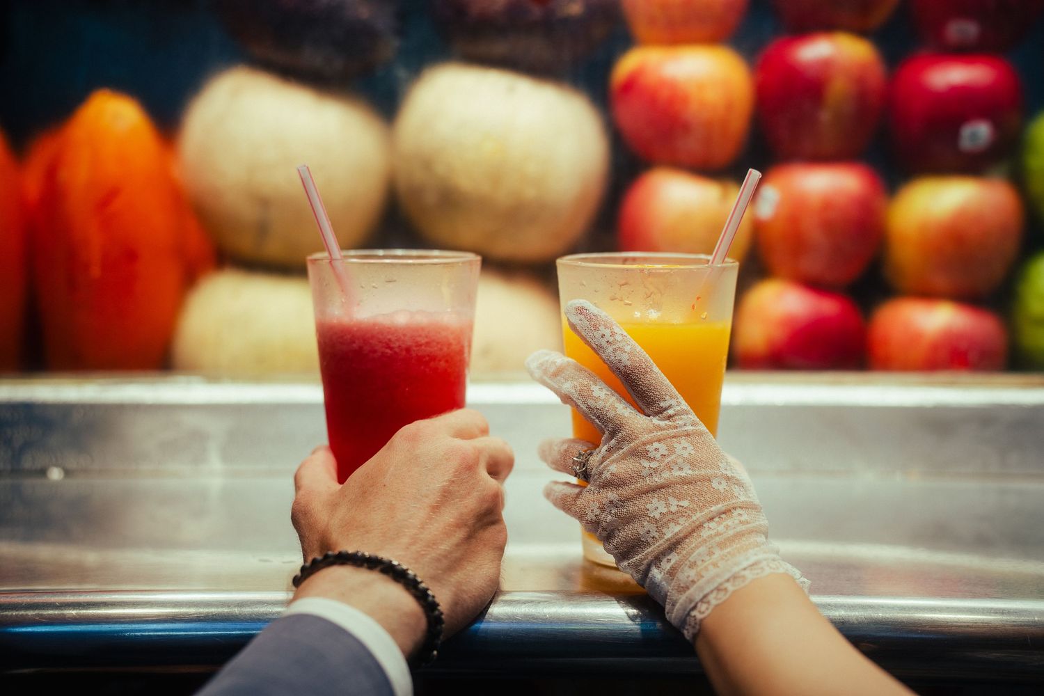 Close-up of a bride and groom holding fresh fruit juices at a colorful Taiwanese juice stand in Taipei