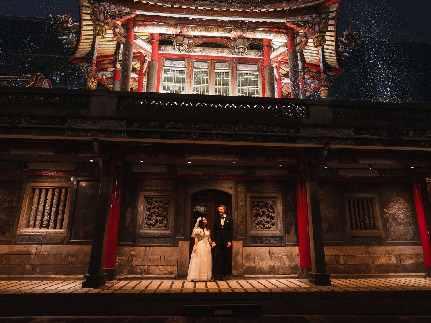 Cinematic portrait of a bride and groom surrounded by traditional Taiwanese temple architecture in Taipei