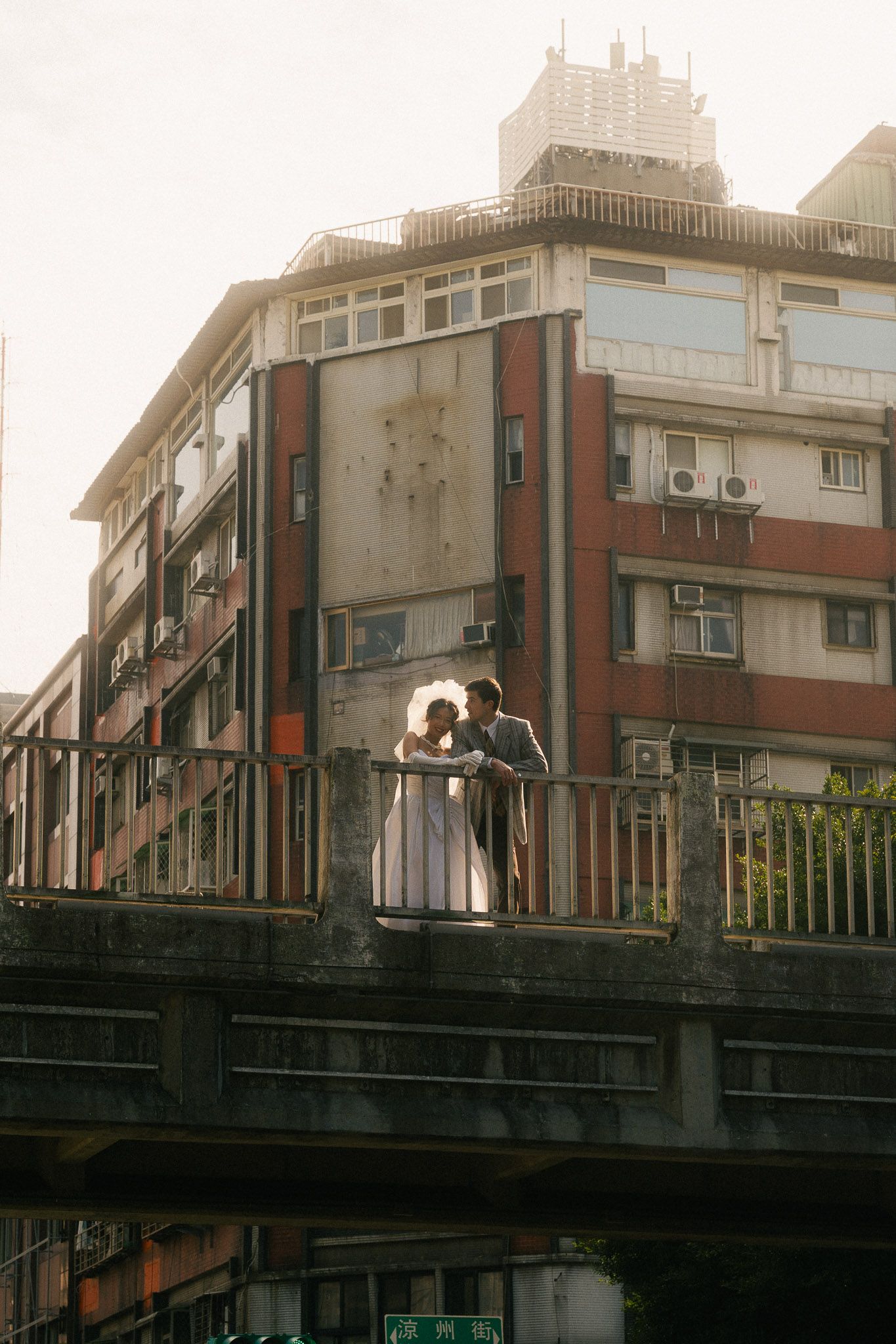 Wide portrait of Emily and Nik standing together on an old bridge in Dadaocheng, Taipei