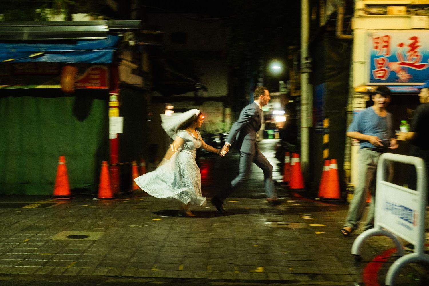 Couple running hand in hand through the streets of Taipei during a cinematic night pre-wedding photoshoot.