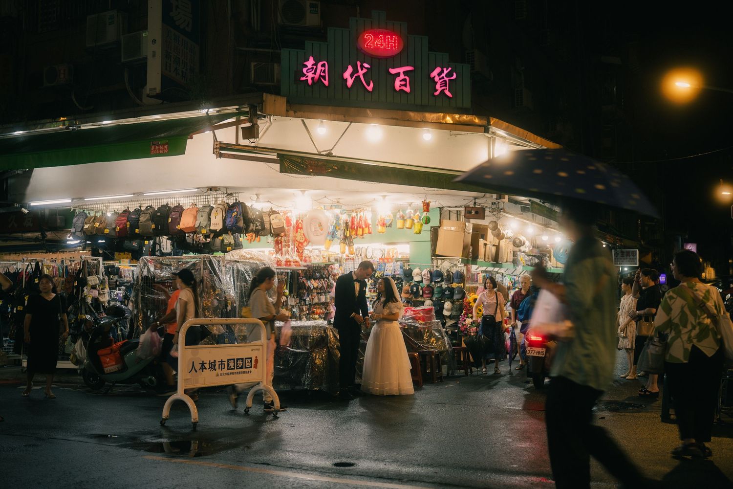 Bride and groom surrounded by local shoppers and street stalls at a Taipei night market