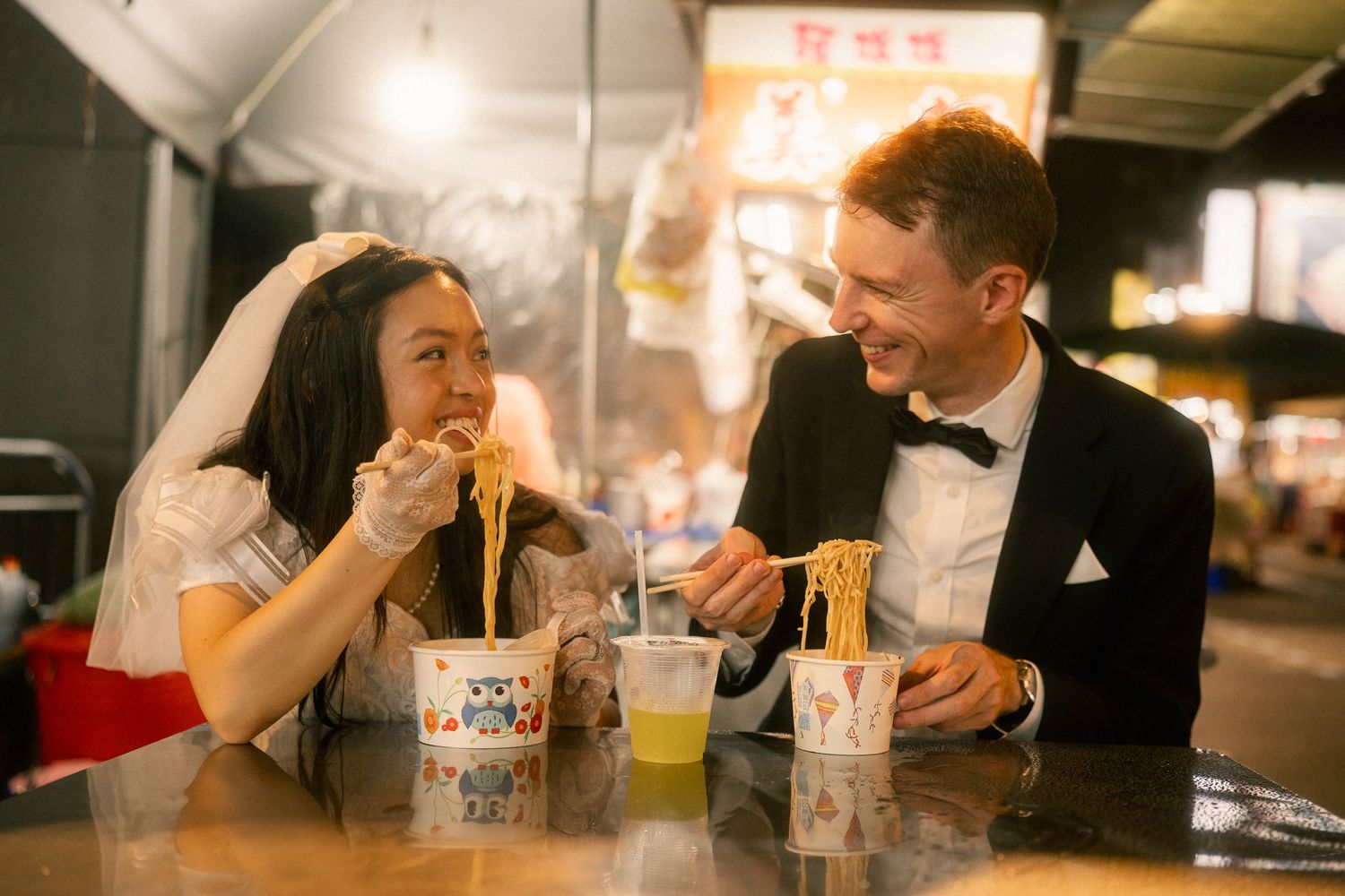 Bride and groom laughing together over bowls of noodles during a candid Taipei pre-wedding session