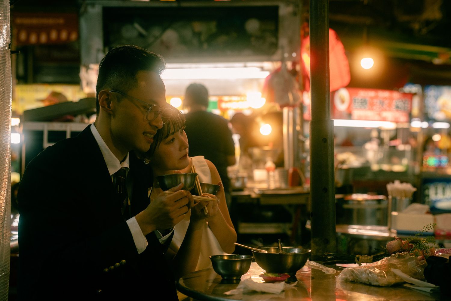 Bride smiling while sharing food with her groom during a candid Taipei night market photoshoot