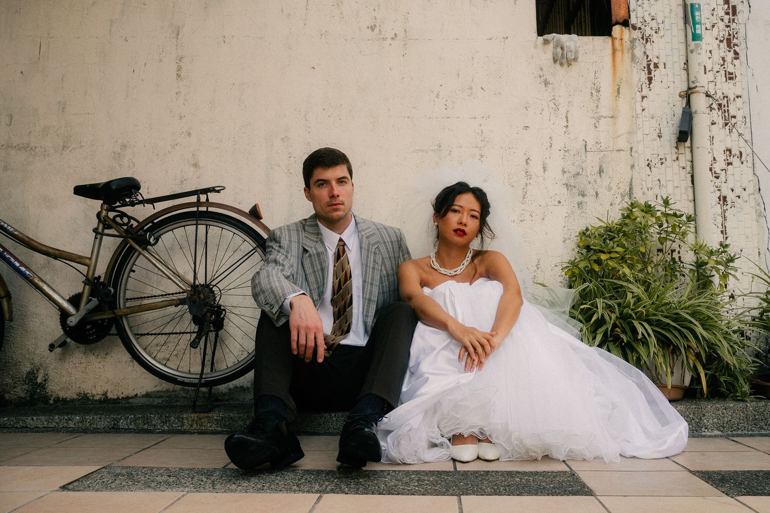 Cinematic portrait of Emily and Nik seated beside a vintage bicycle during their Taipei pre-wedding session