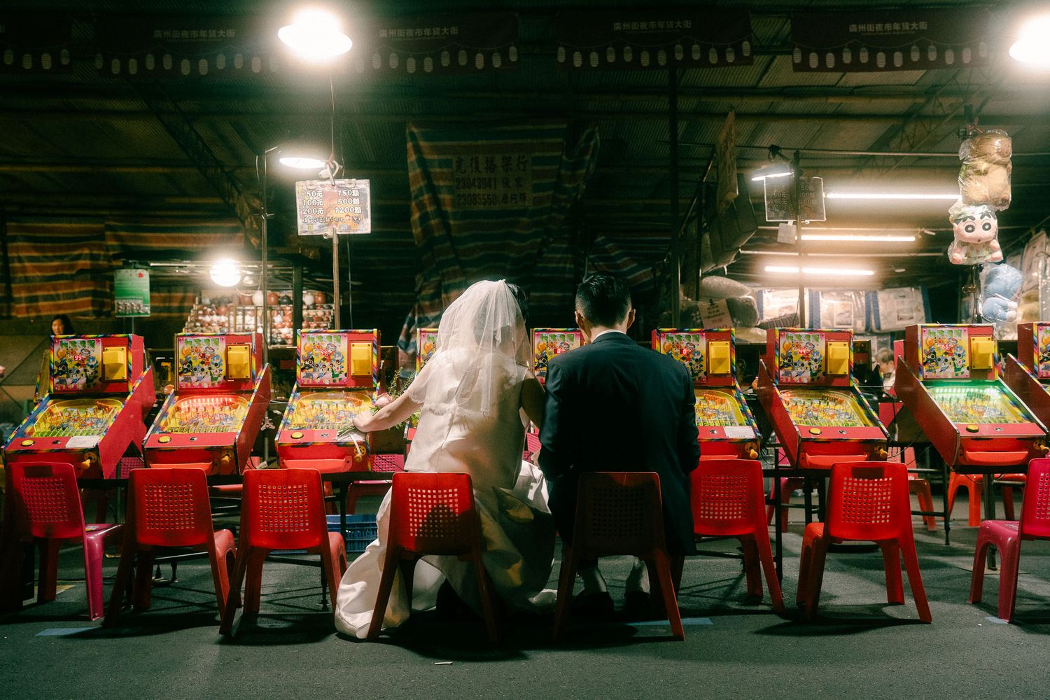 Sunny and Leo sitting together at vintage arcade games during their Huaxi Street Night Market pre-wedding session