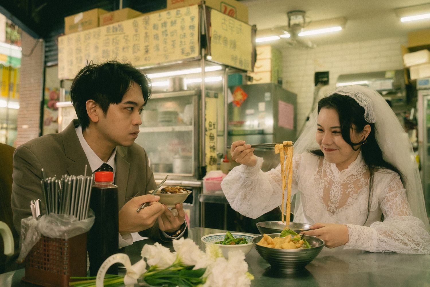 Bride and groom eating noodles together at a traditional Taiwanese food stall during their Dihua Street photo session