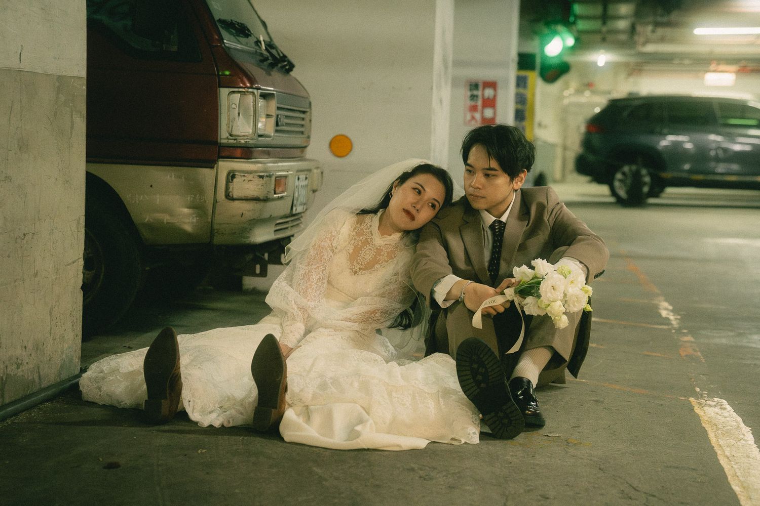 Cinematic Taipei pre-wedding photography of a bride and groom sitting in an urban parking garage