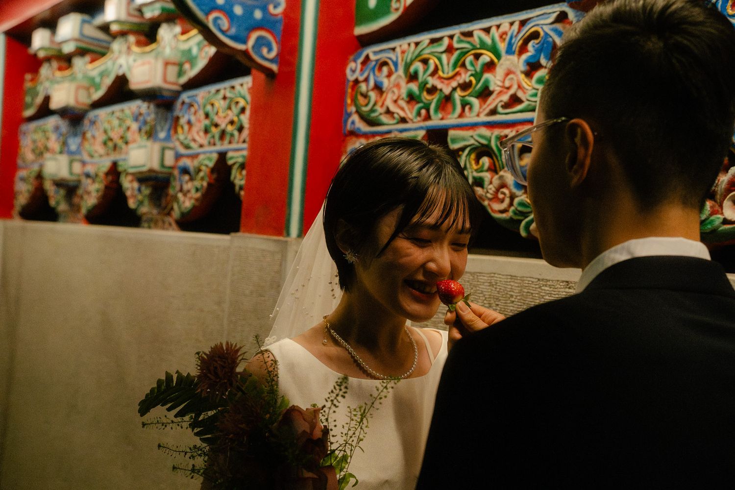 Taipei pre-wedding couple sharing a strawberry in front of colorful traditional temple details