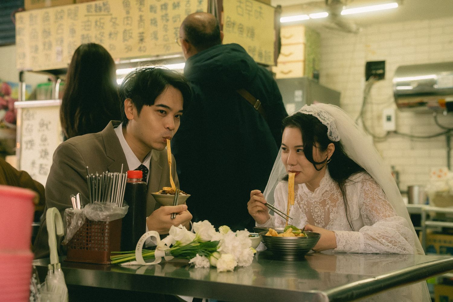 Bride and groom eating noodles together at a traditional Taiwanese food stall during their Dihua Street photo session