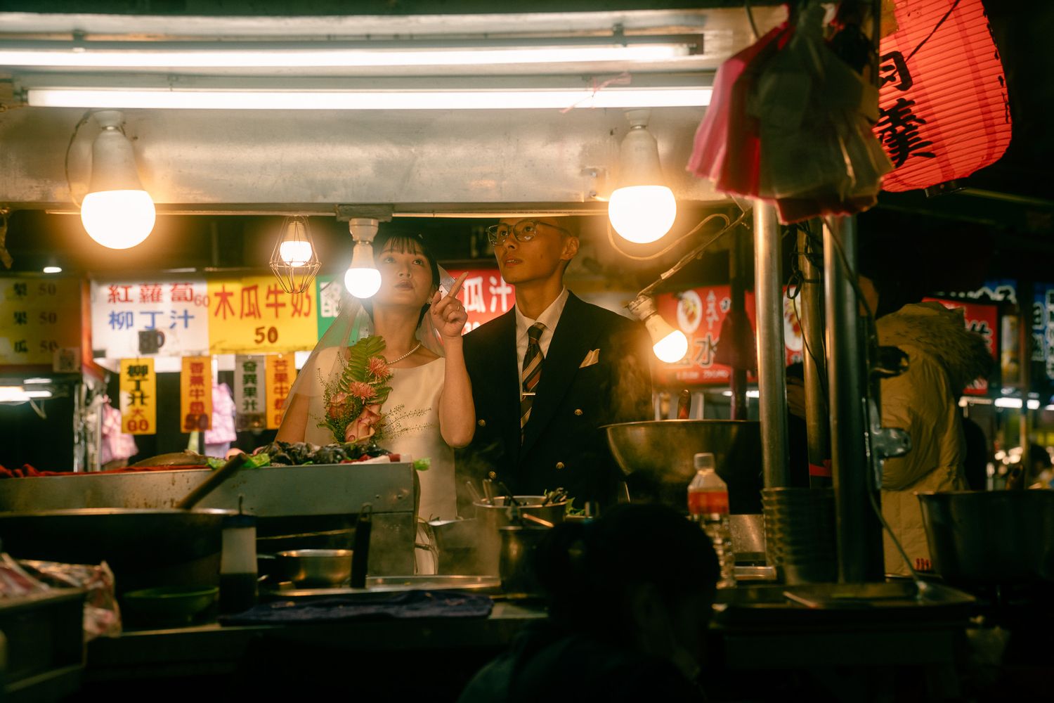 Sunny and Leo photographed behind a steaming food stall during their Taipei night market pre-wedding session