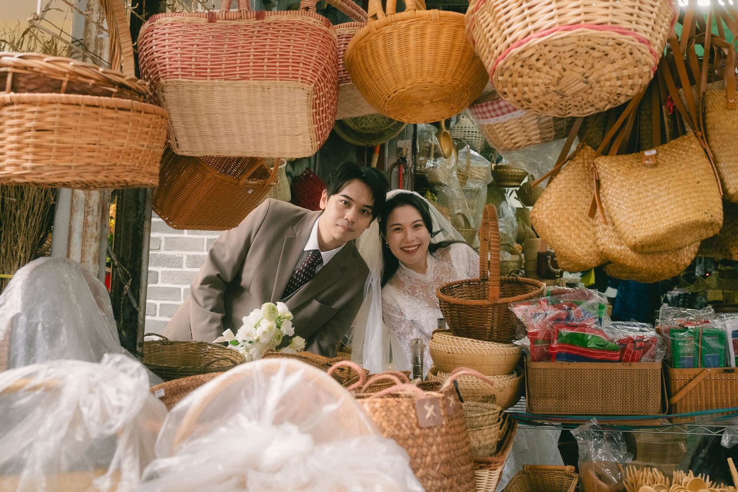 Bride and groom peeking through woven baskets at a traditional shop during a Dihua Street pre-wedding session