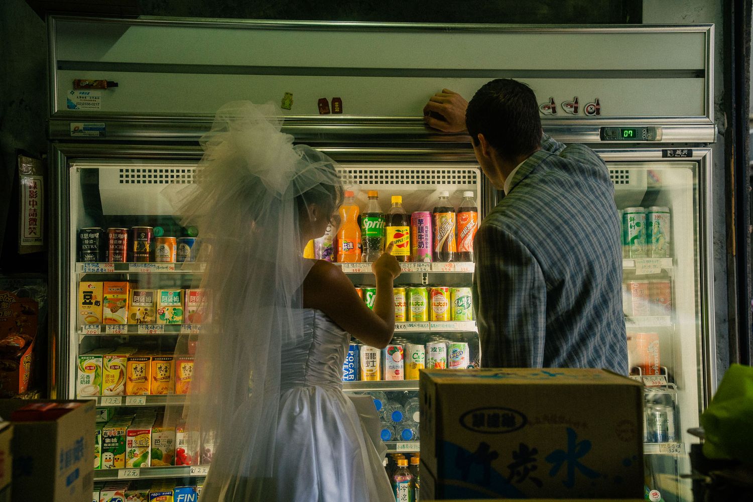 Emily and Rik looking through a drink refrigerator during their cinematic Taipei couple photoshoot