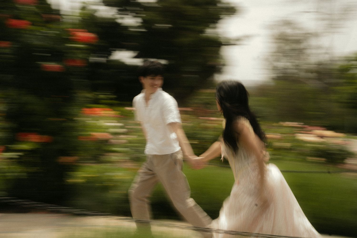 Taiwanese couple running across rose garden for their engagement photoshoot with Francis Cinema