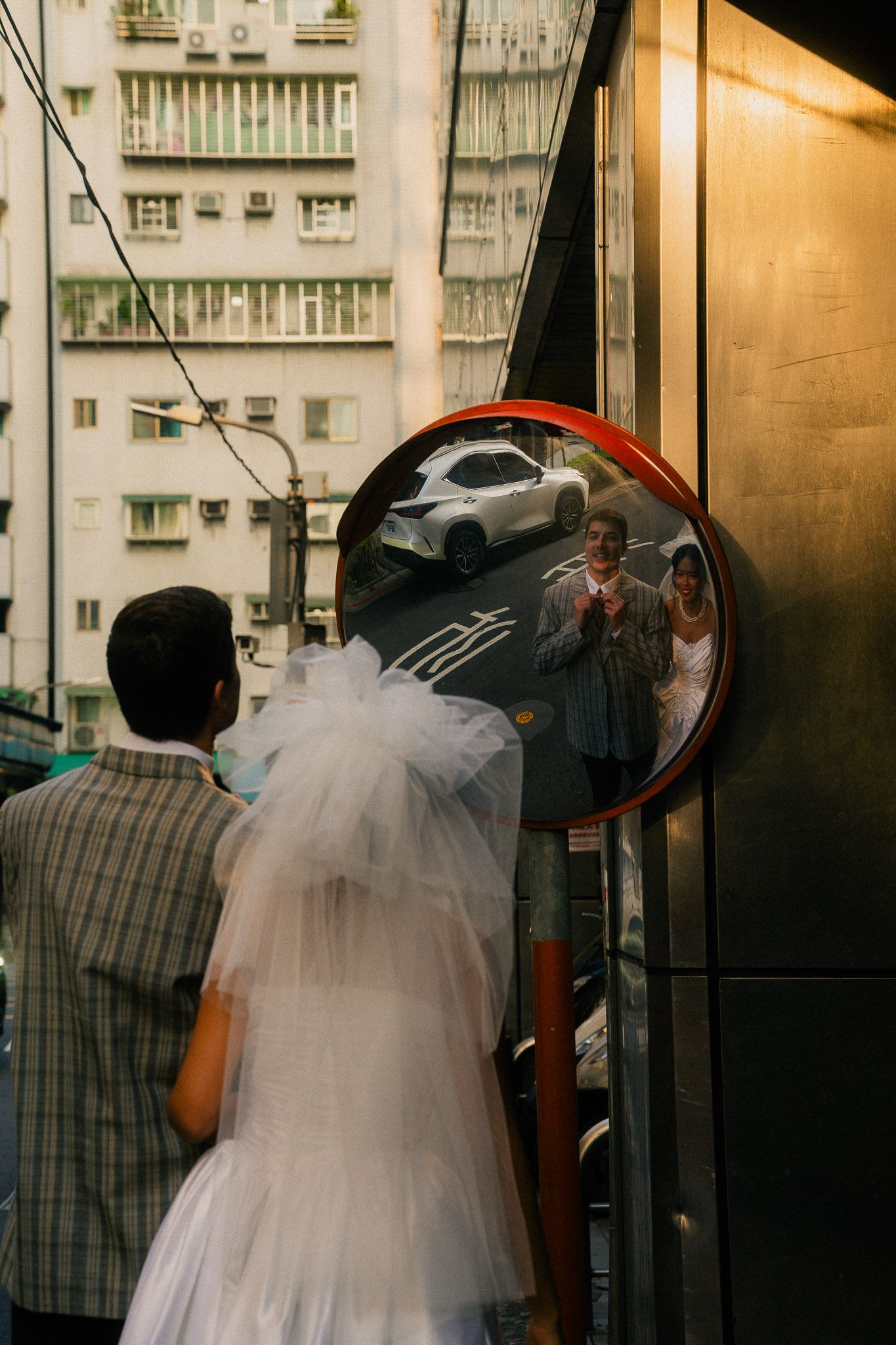 Emily and Rik reflected in a convex street mirror during their cinematic Taipei pre-wedding photoshoot near Dihua Street