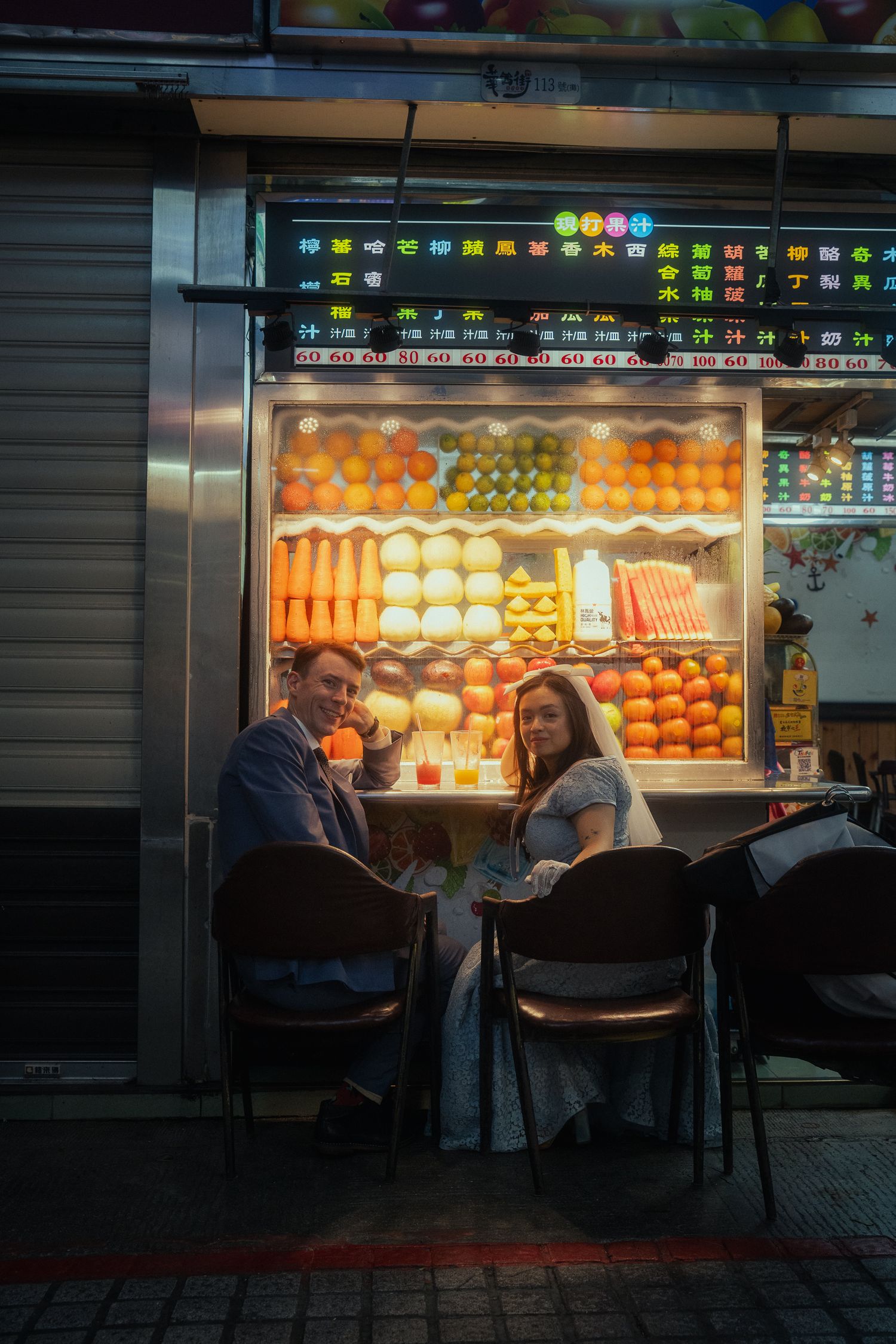 Bride and groom sitting outside a traditional fruit juice stand during a cinematic Taipei pre-wedding session