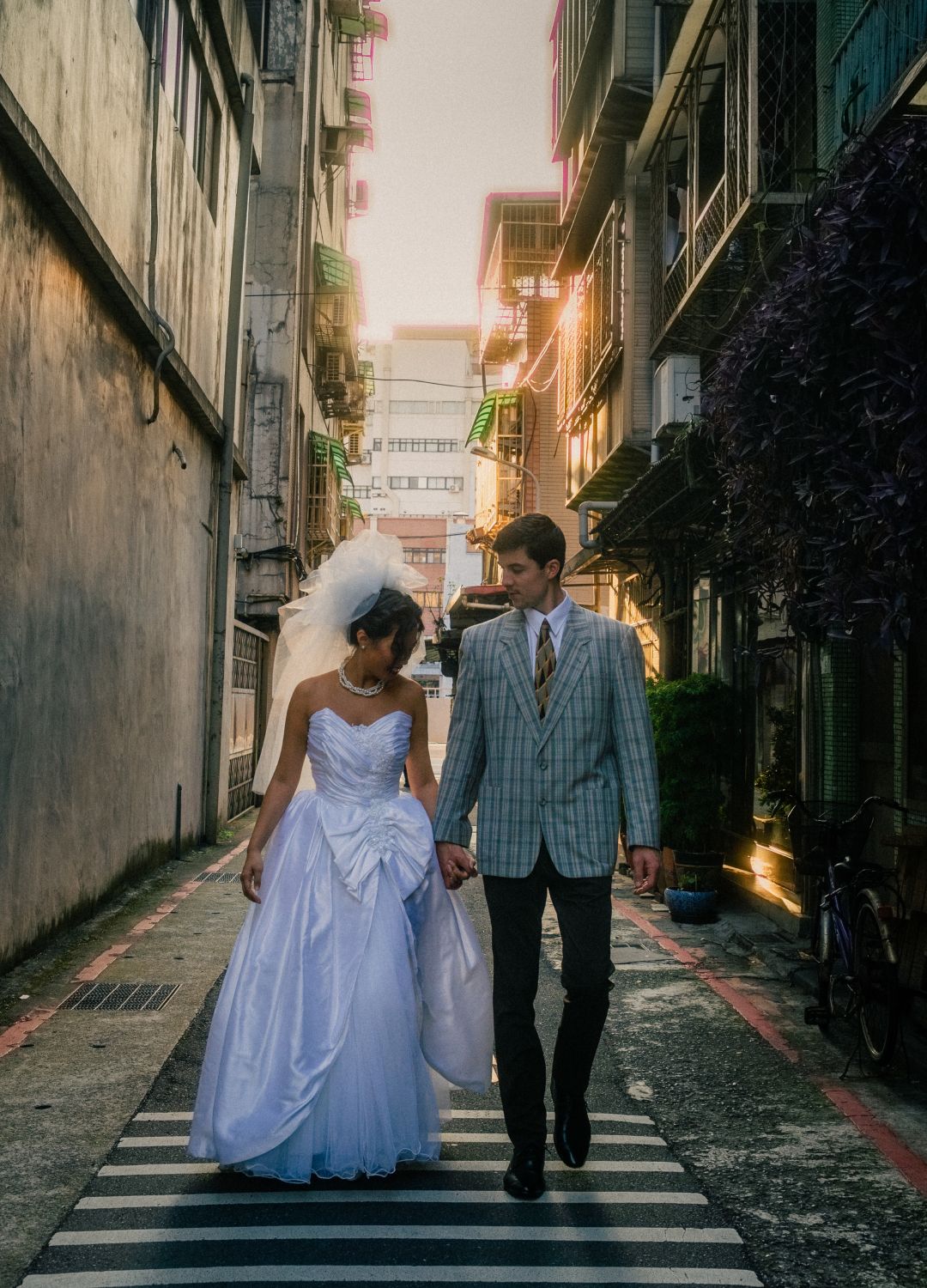 Wide cinematic portrait of Emily and Rik standing on a bridge surrounded by old Taipei buildings