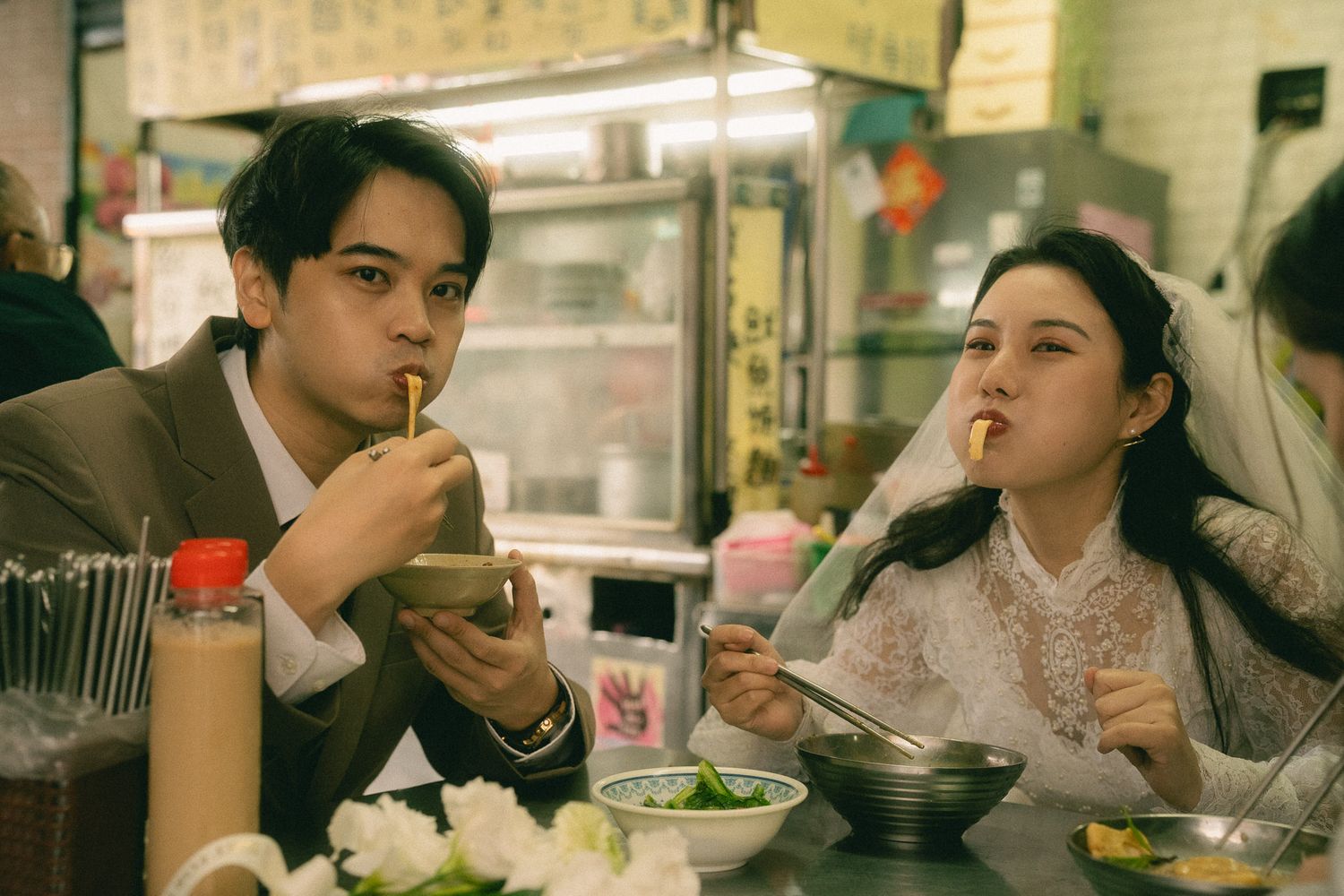 Bride and groom eating noodles together at a traditional Taiwanese food stall during their Dihua Street photo session