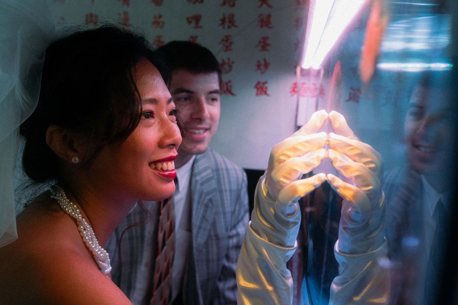 Emily smiling beside a reflective fish tank with Nik during their East Asian cinema-inspired pre-wedding session