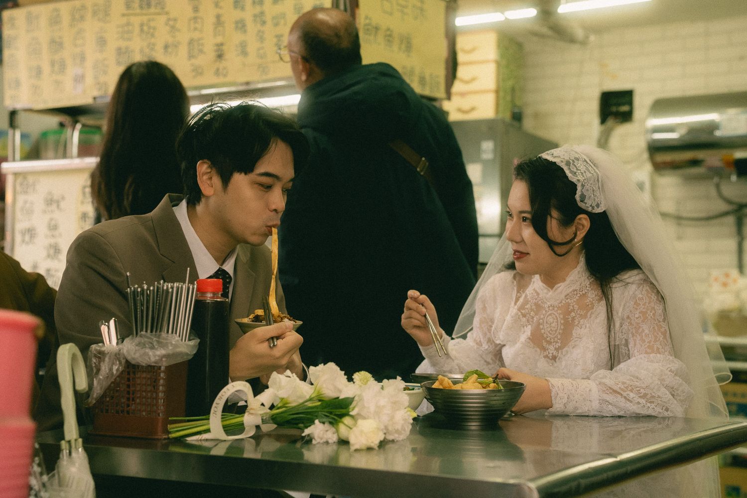 Bride and groom eating noodles together at a traditional Taiwanese food stall during their Dihua Street photo session