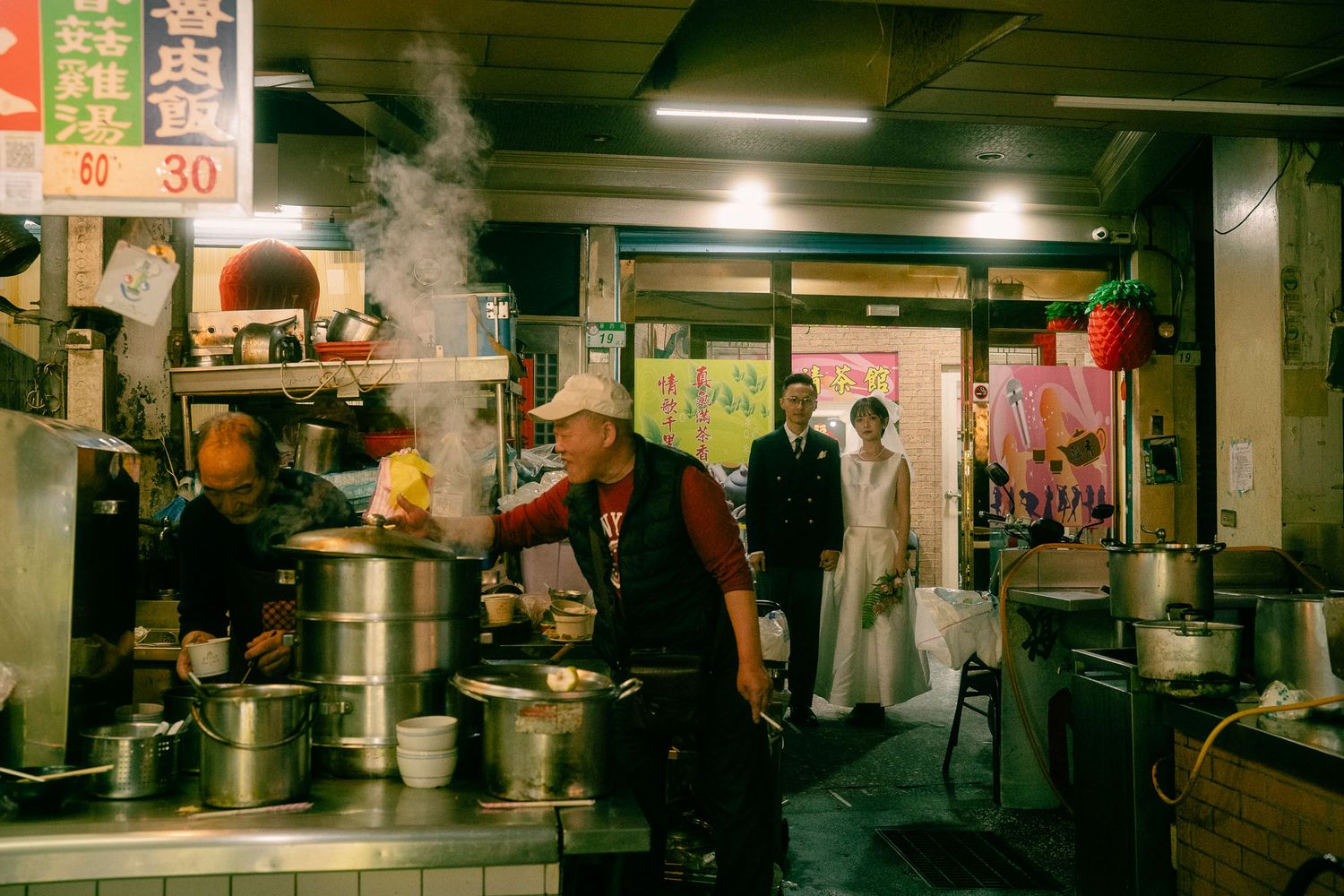 Sunny and Leo photographed behind a steaming food stall during their Taipei night market pre-wedding session