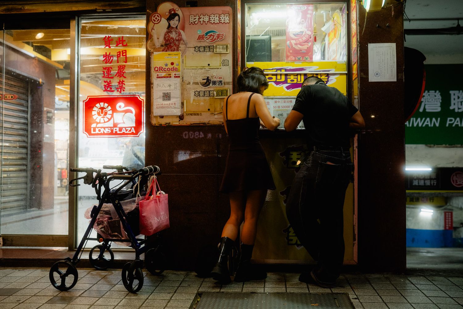 Couple buying and scratching lottery tickets at a Taiwan Lottery shop in Ximending, Taipei