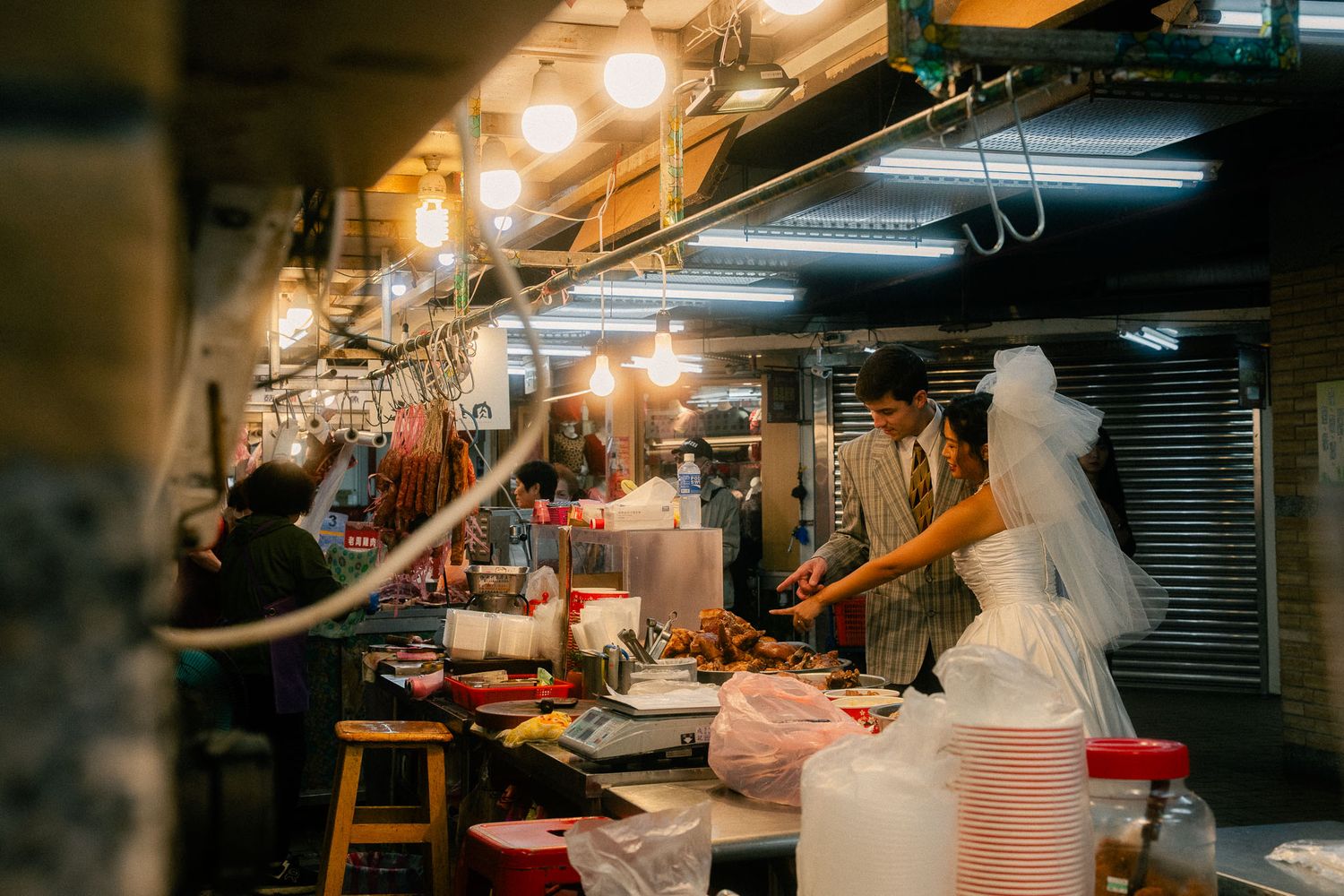 Couple choosing street food together inside a traditional Taipei market during their documentary-style pre-wedding session