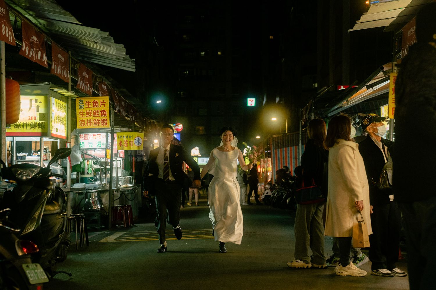 Bride and groom running beneath glowing street lights during a cinematic night photoshoot in Taipei