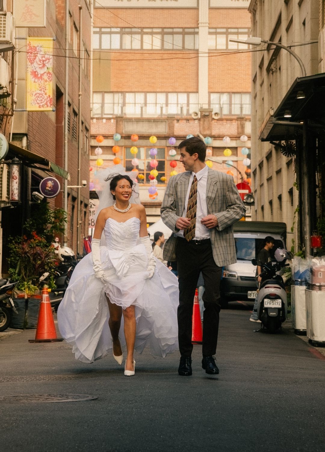 Emily and Nik walking through an old Taipei neighborhood in vintage-inspired wedding outfits