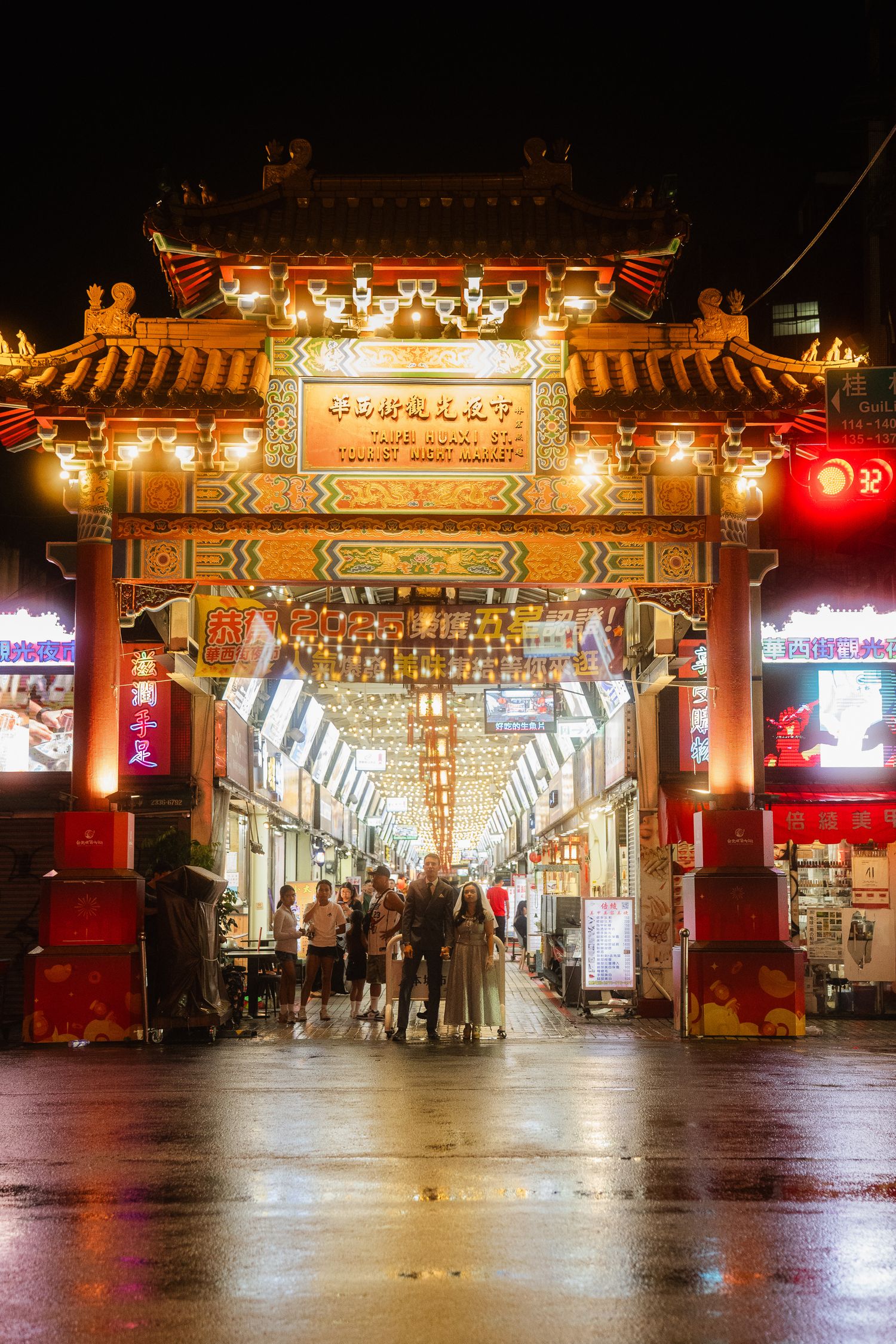 Bride and groom standing beneath the illuminated entrance of Huaxi Street Night Market during their Taipei pre-wedding session.