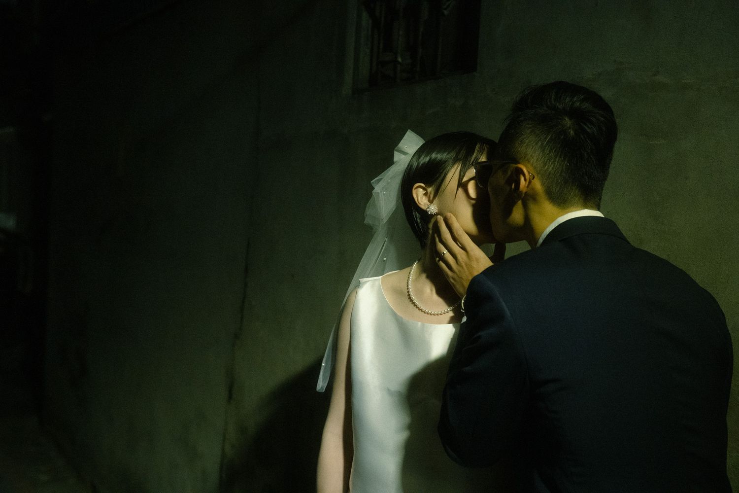 Taipei pre-wedding portrait of Sunny and Leo kissing beneath a narrow beam of light near Huaxi Street Night Market