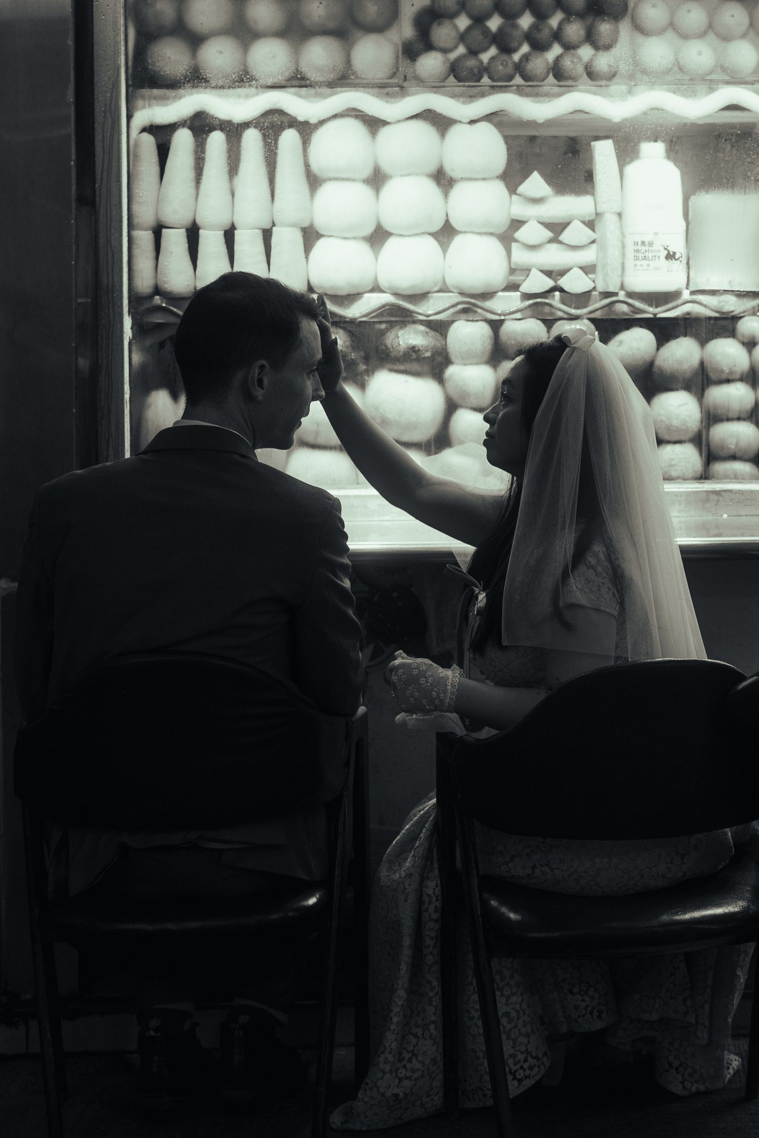 Black and white cinematic portrait of a couple beside a fruit stand during their Huaxi Street Night Market pre-wedding session.