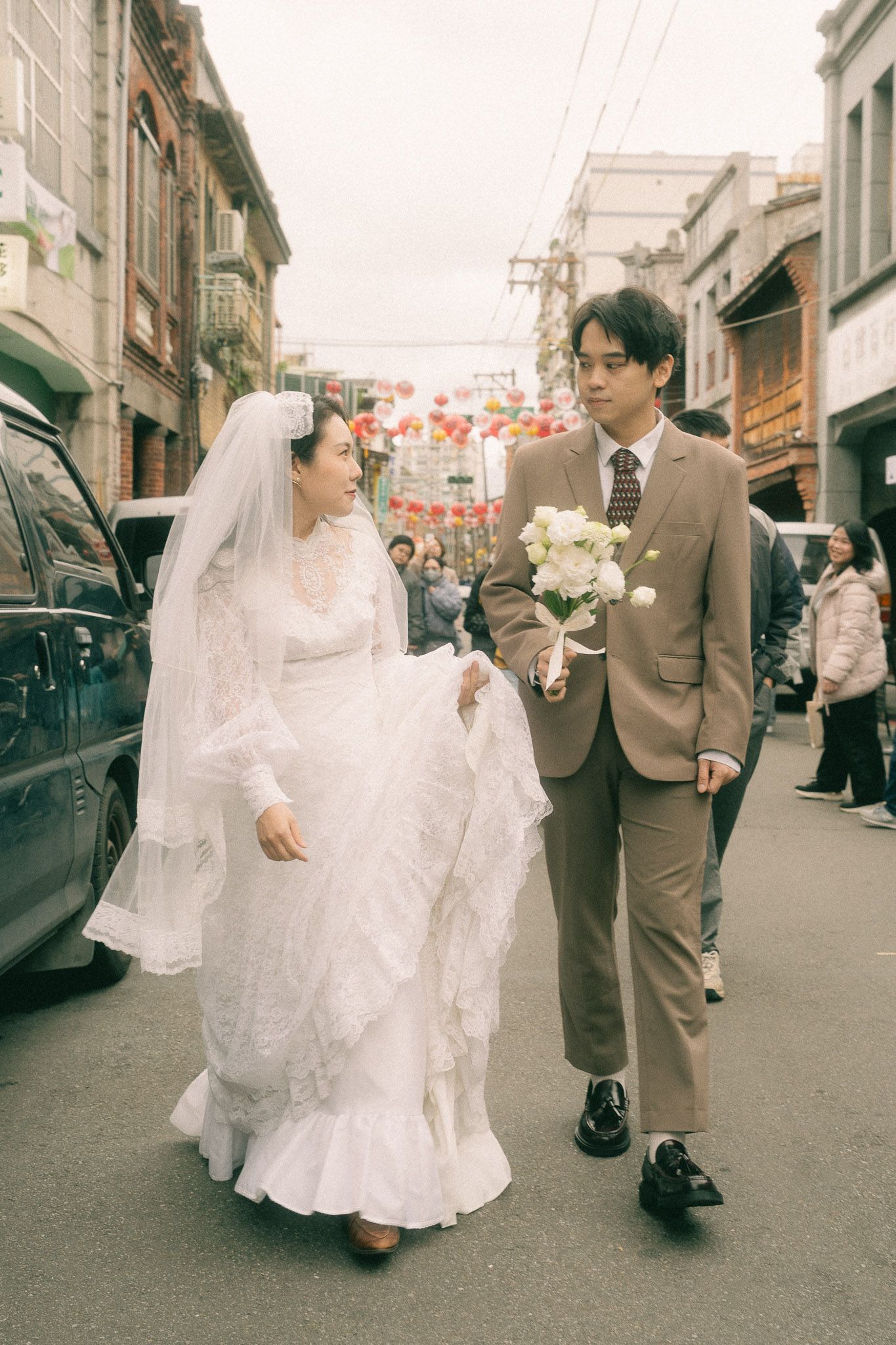 Bride and groom walking through crowded Dihua Street and posing in a quiet Dadaocheng alley during their Taipei session