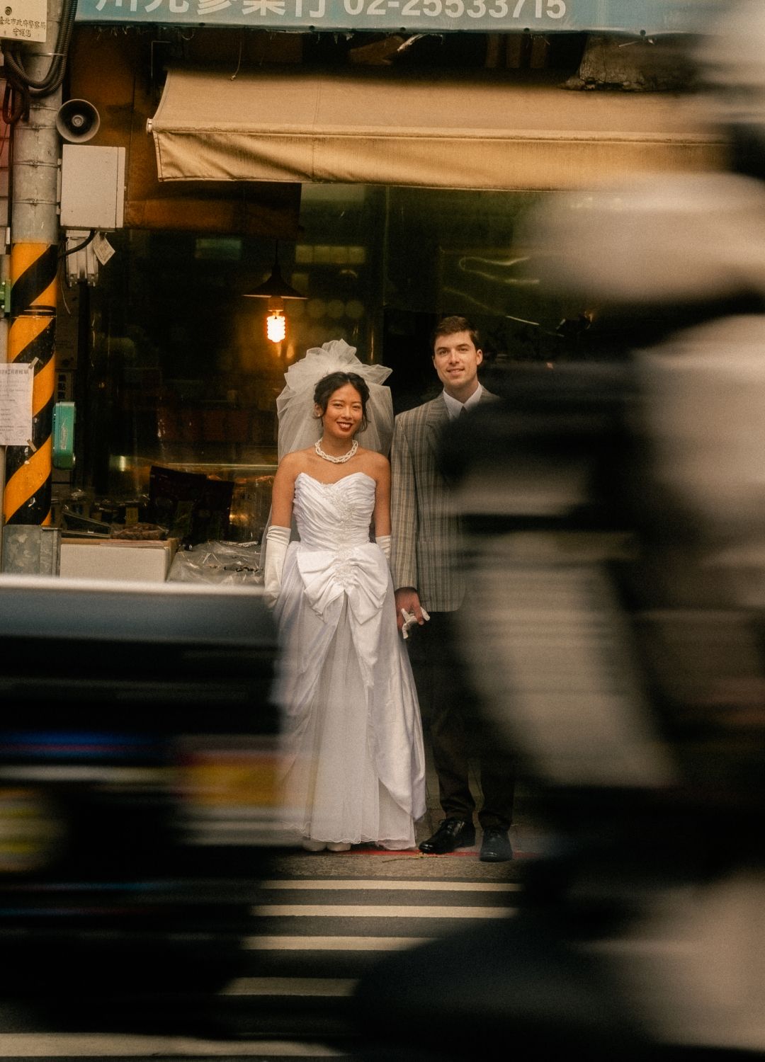Emily and Nik walking past scooters and local shops during their Dadaocheng engagement session