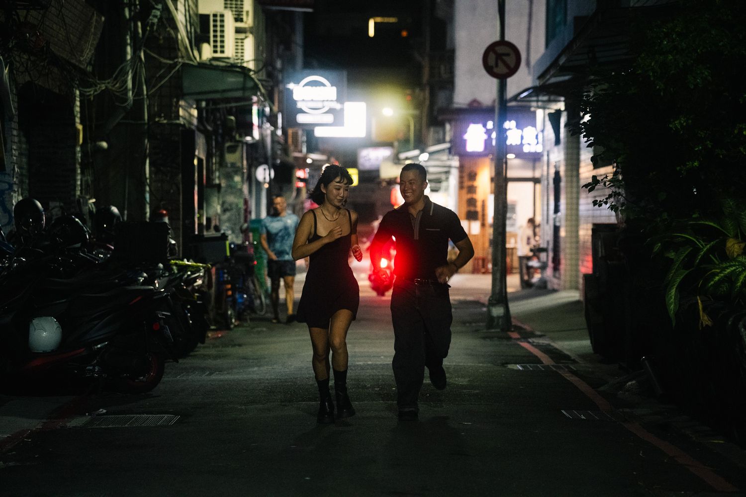 Couple racing down a quiet Ximending alley during their cinematic Taipei couple photoshoot