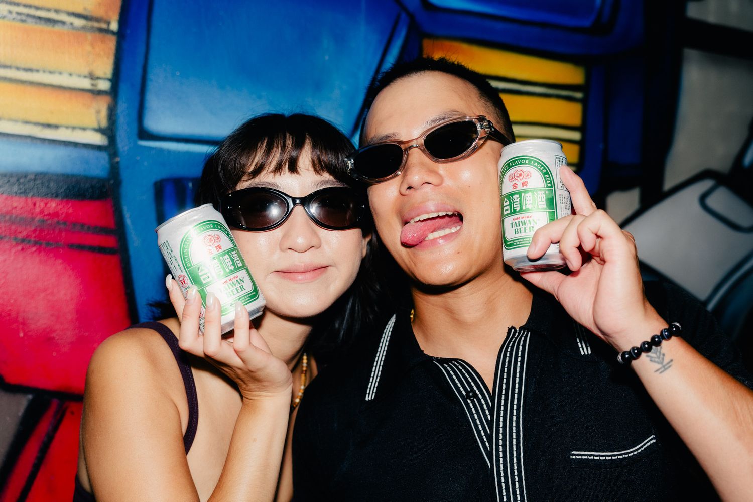 Couple wearing sunglasses and holding Taiwan Beer during a flash photography session in Ximending, Taipei