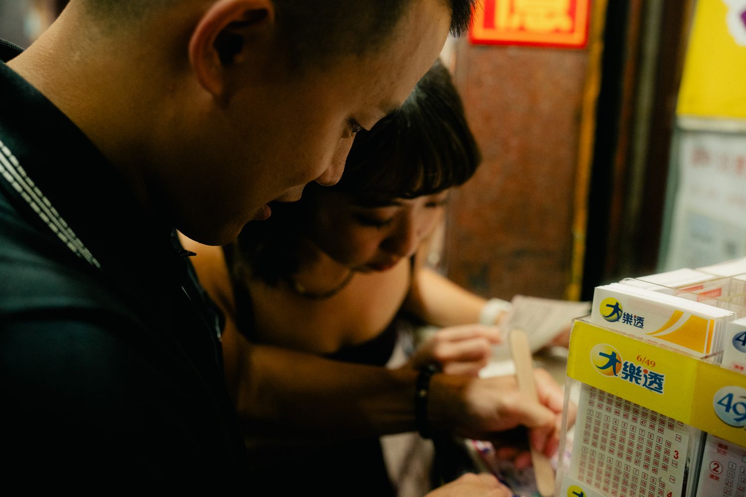 Couple scratching Taiwan lottery tickets together during their Ximending date night photoshoot in Taipei
