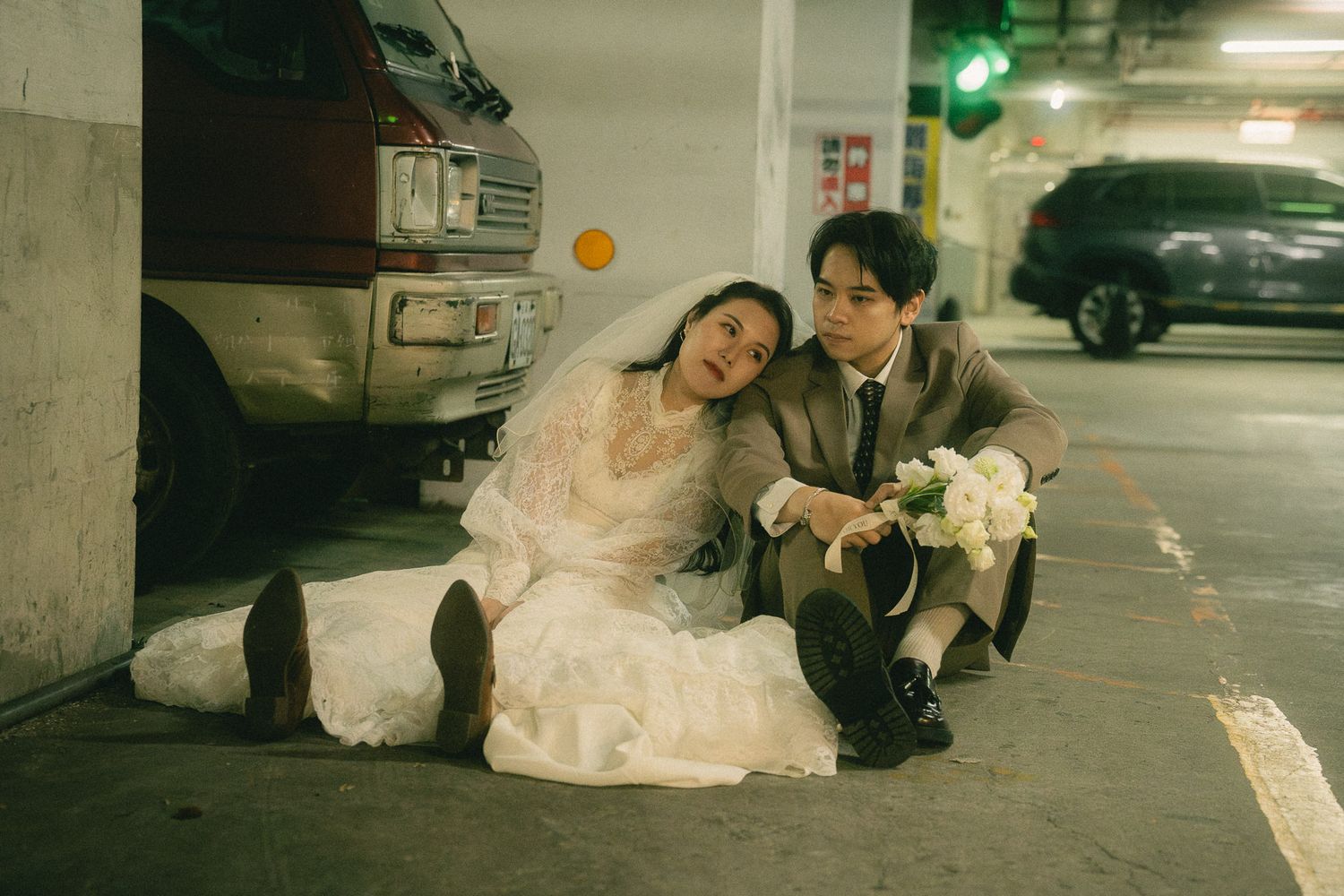 Cinematic Taipei pre-wedding photography of a couple sitting together in an urban parking garage