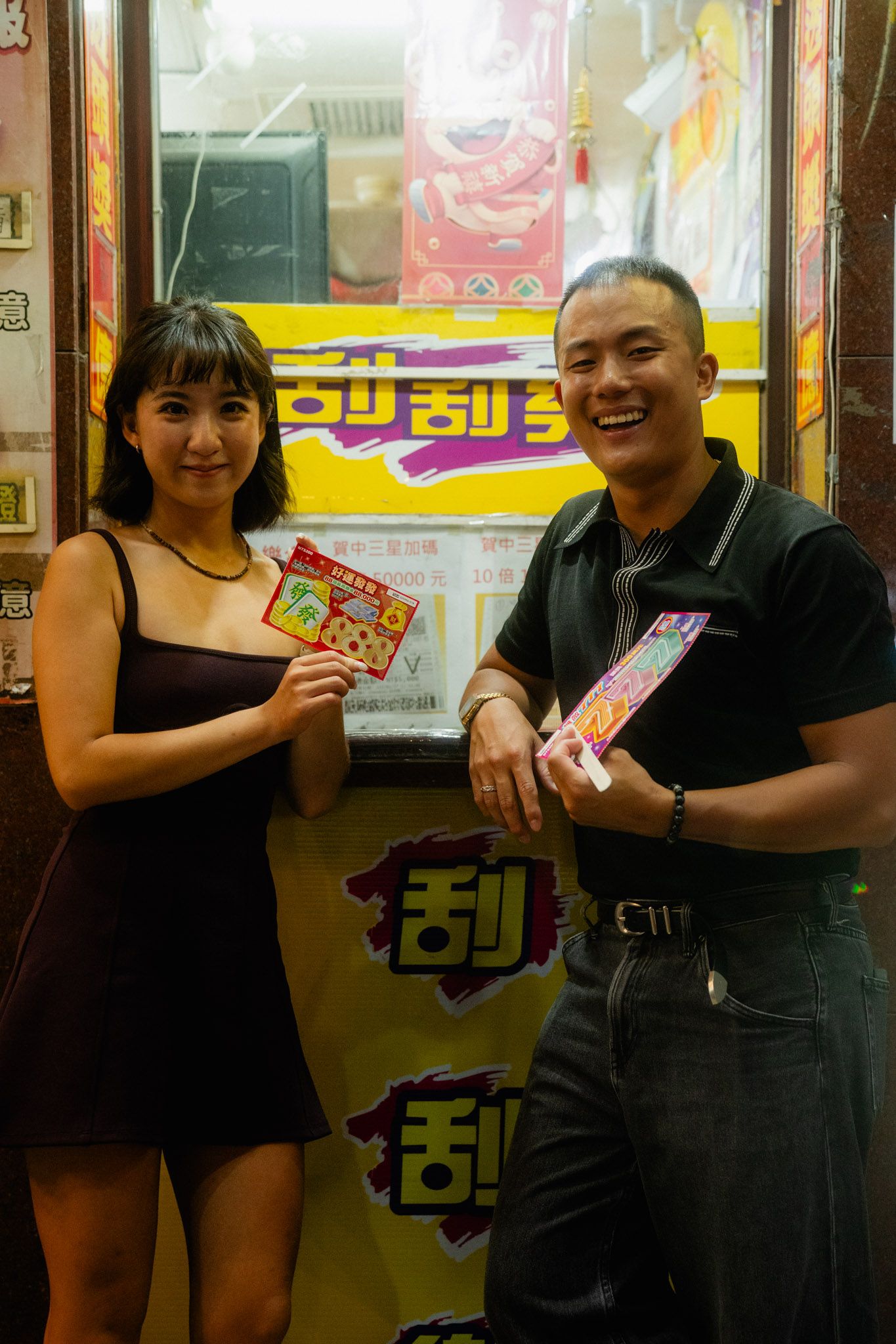 Couple showing their Taiwan scratch-off lottery tickets during a playful Ximending couple photoshoot