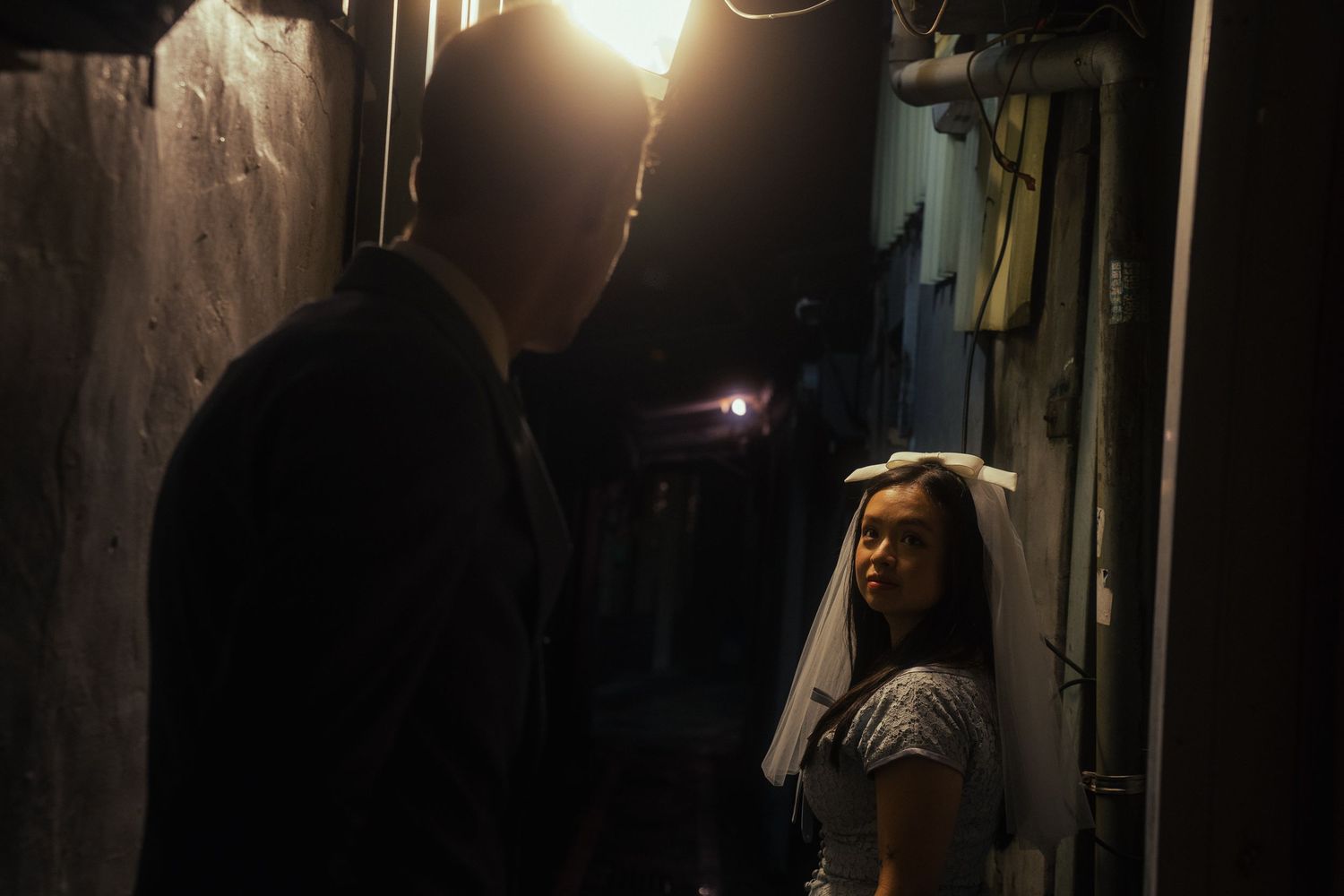 Bride in a vintage wedding dress standing in a dark Taipei alley during a cinematic night photoshoot