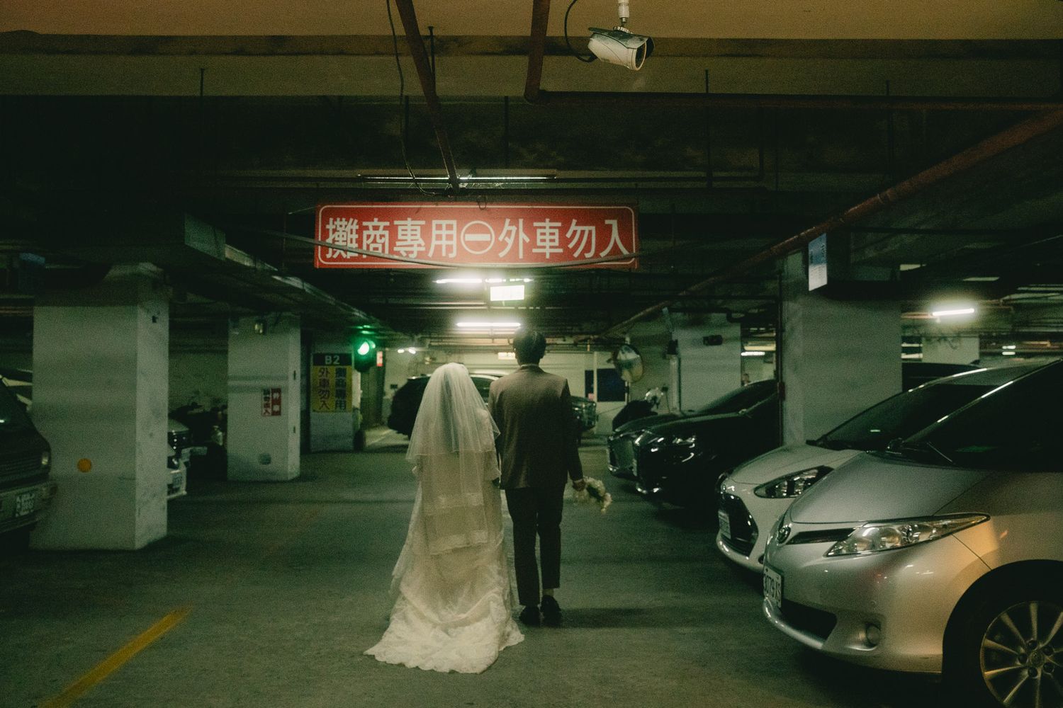 Bride and groom walking through a Taipei parking garage during a cinema-inspired pre-wedding photography session