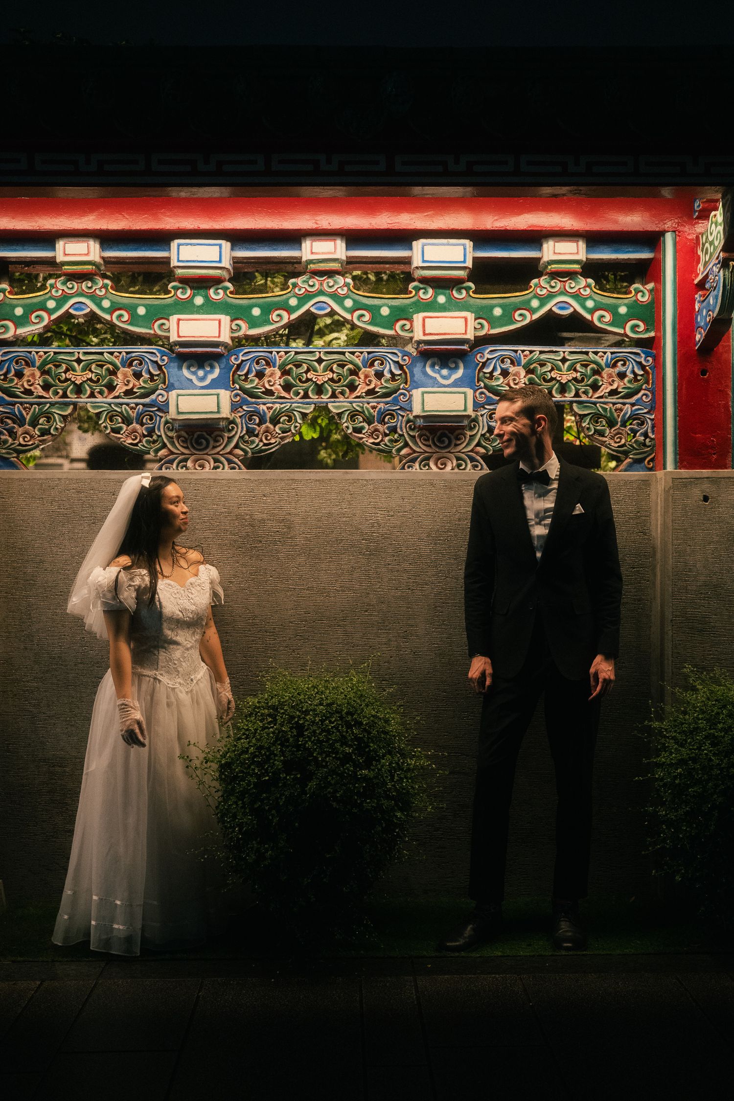 Bride and groom facing each other beside traditional Taiwanese temple architecture in Taipei