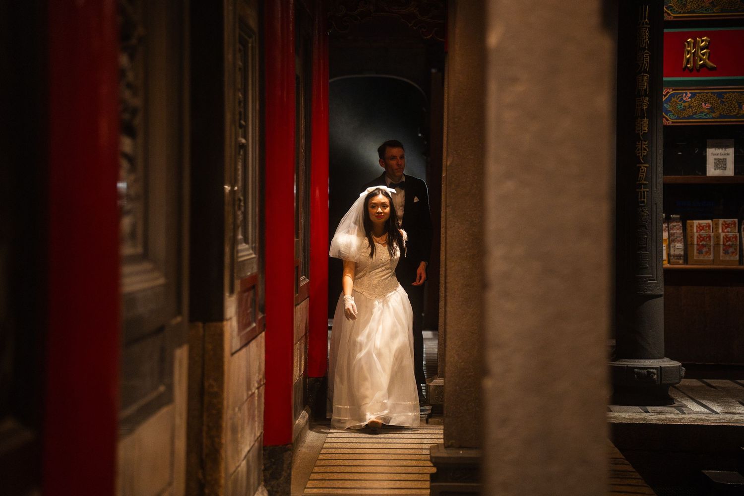 Bride walking through a traditional Taipei temple with her groom following behind