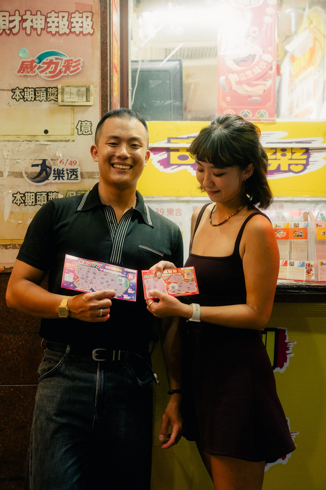 Couple celebrating their winning scratch-off lottery tickets during a Ximending night photoshoot in Taipei