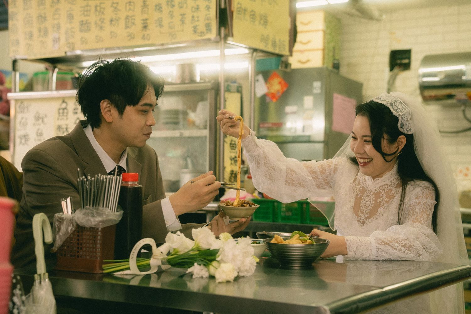 Bride and groom eating noodles together at a traditional Taiwanese food stall during their Dihua Street photo session