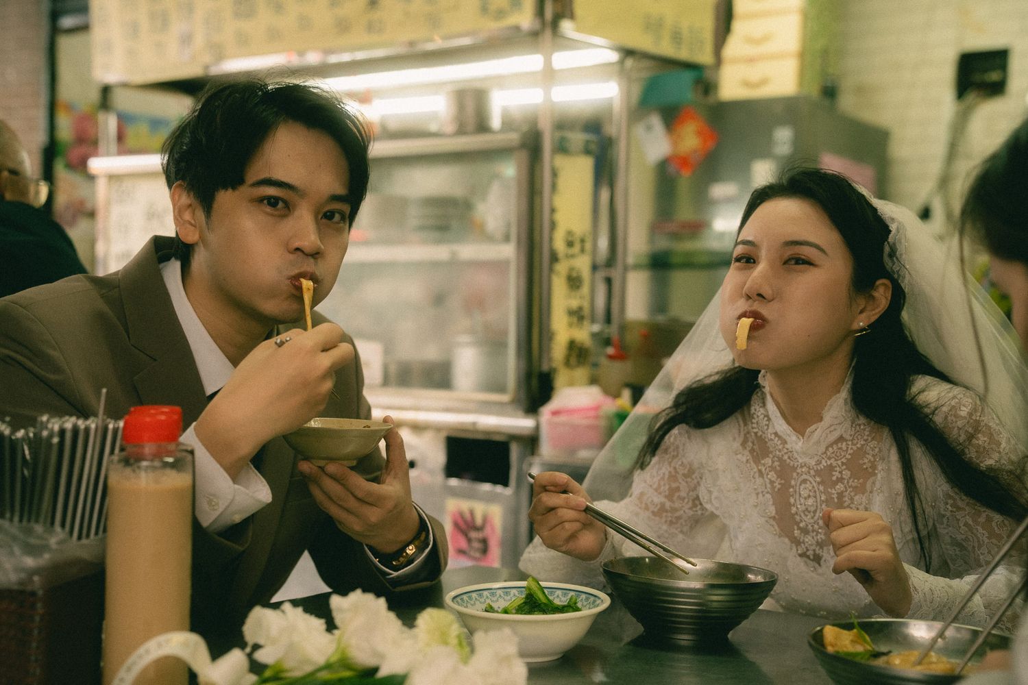 Bride and groom eating noodles together at a traditional Taiwanese food stall during their Dihua Street photo session