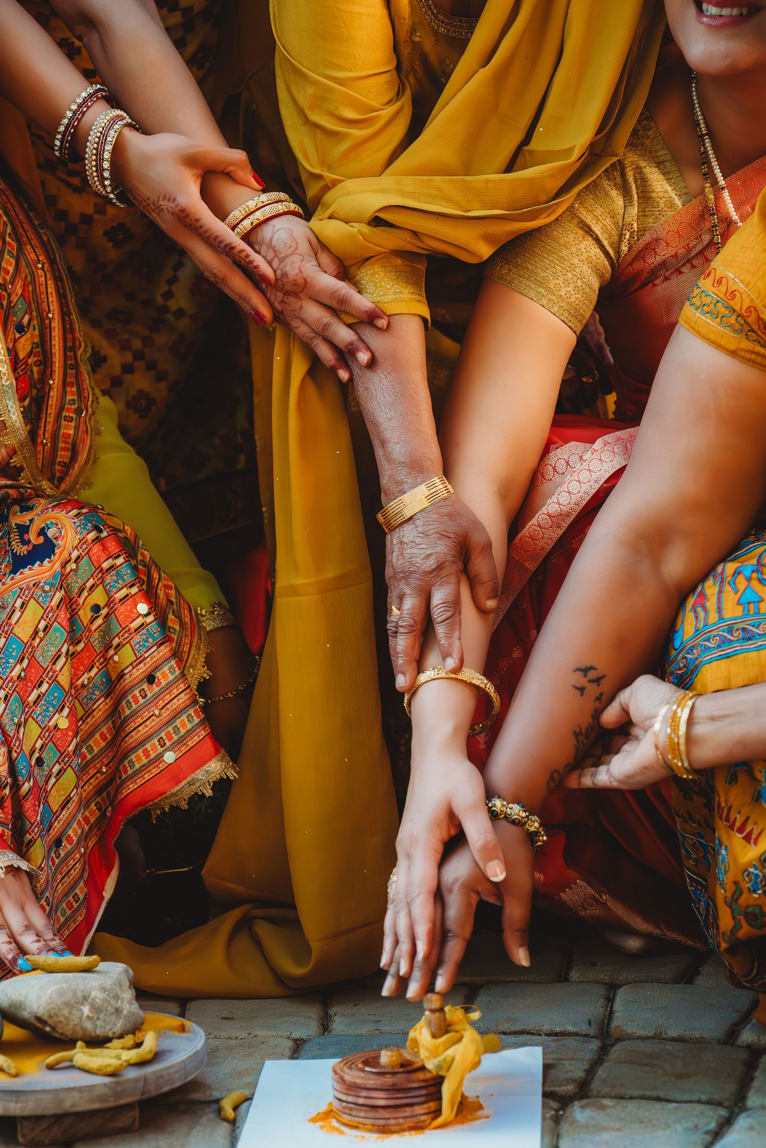 Indian wedding ceremony with women in vibrant yellow and red saris adorned with gold bangles. destination