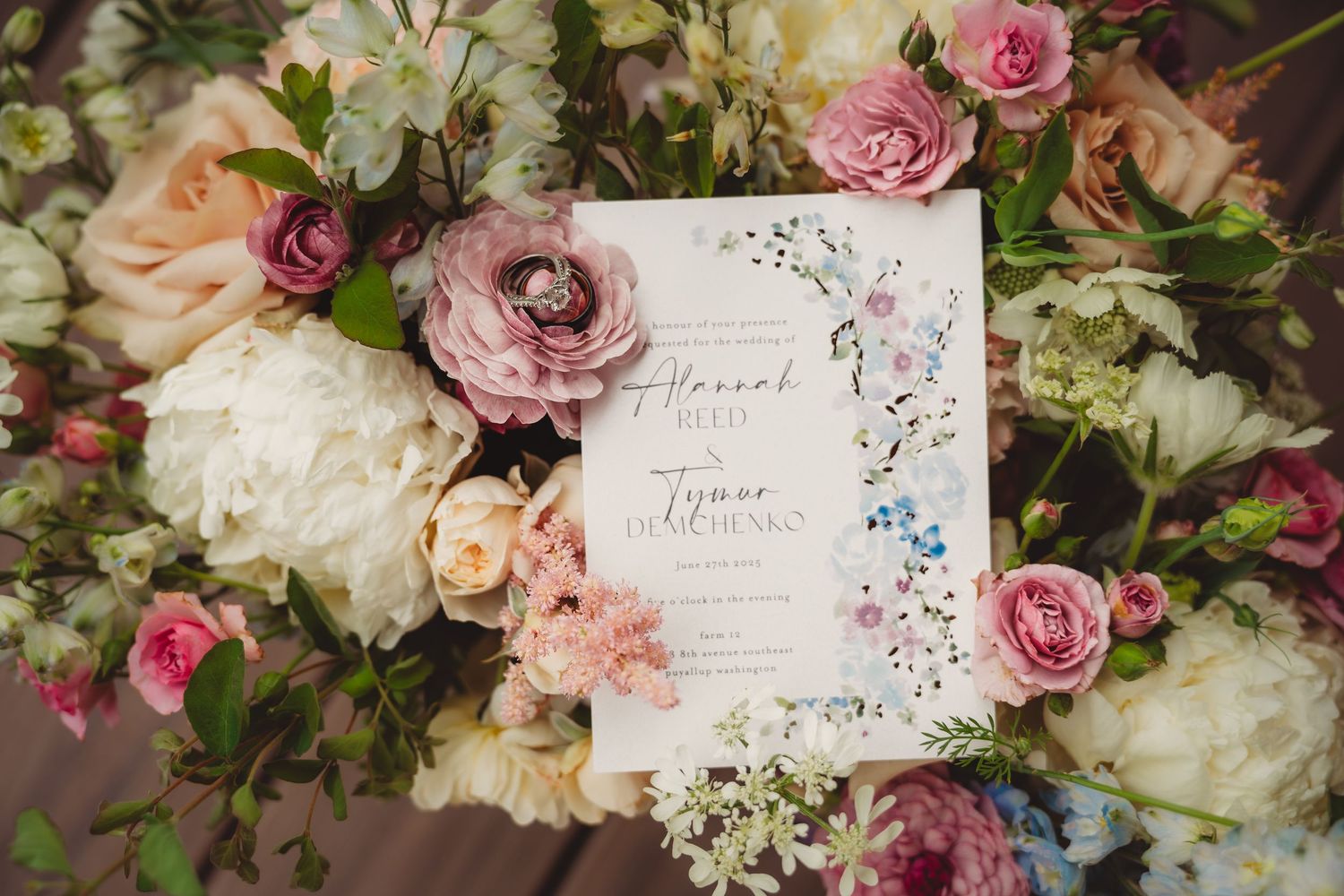 Floral wedding invitation with pink roses and watercolor flowers on a lush arrangement of blush and white blooms.