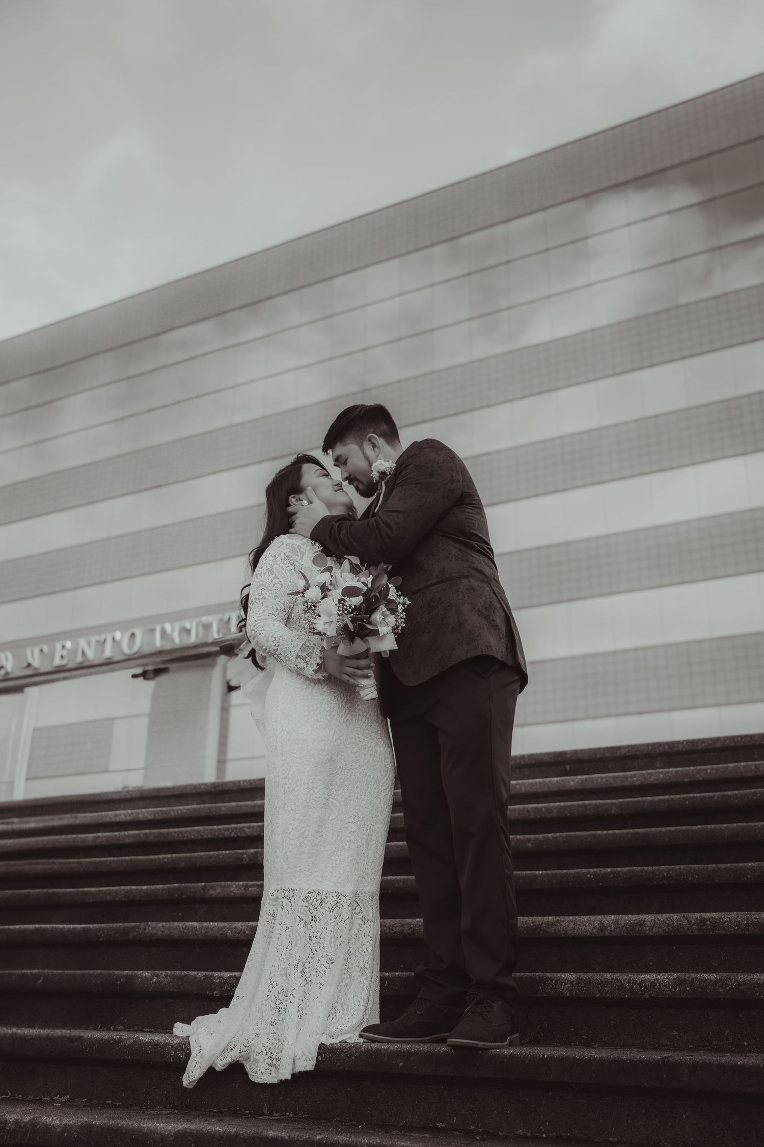 Black and white photo of bride and groom kissing on steps outside a building. downtown Charleston