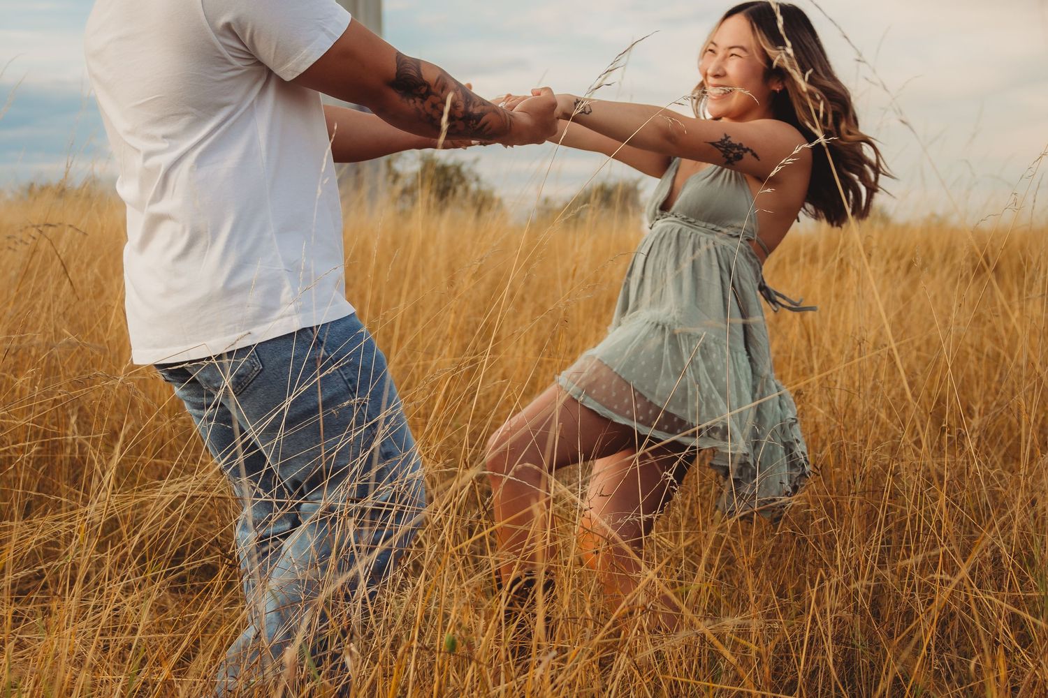 A joyful couple dances and spins together in a golden wheat field on a sunny day.